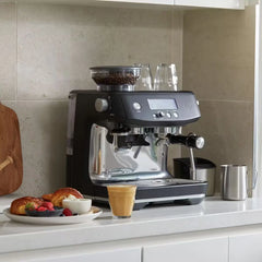 A black Sage Barista Pro espresso machine featuring a built-in grinder, LCD display, steam wand, and a free 3-month coffee subscription, ideal for making barista-quality coffee at home.